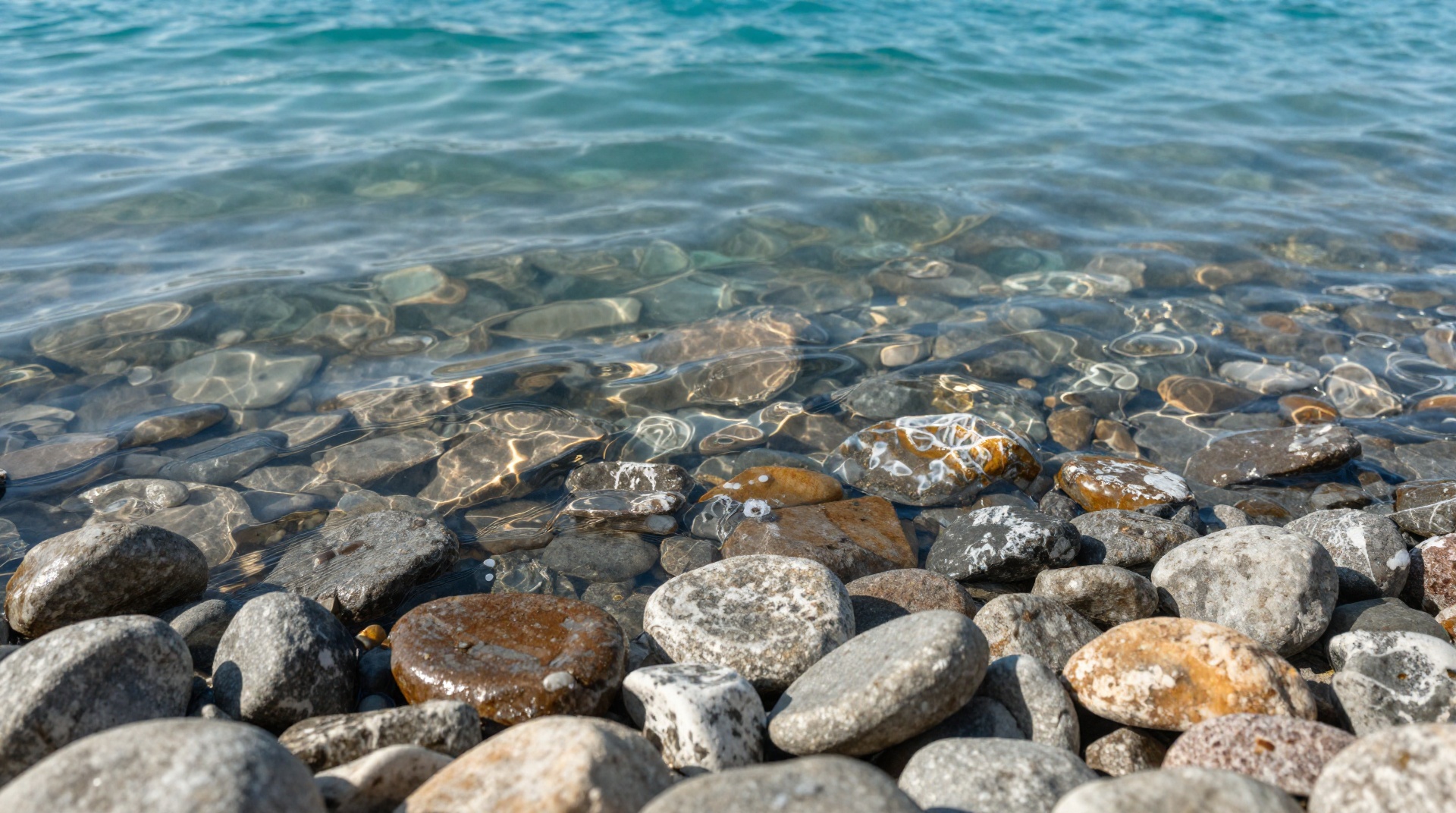 Кристально чистая вода Иссык-Куля с минеральным оттенком Прозрачная вода Иссык-Куля у галечного берега с лёгкими следами соли на камнях